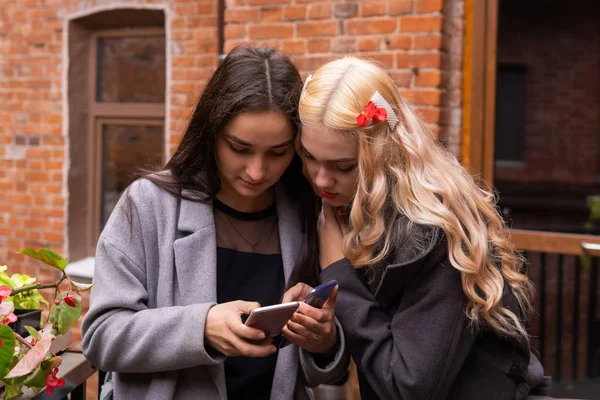 Dos chicas están viendo fotos en un teléfono inteligente — Foto de Stock