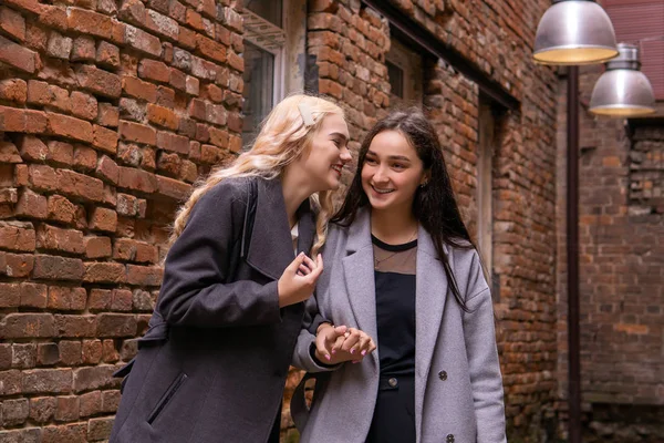 Two young women are secreting about something in the courtyard o — Stock Photo, Image