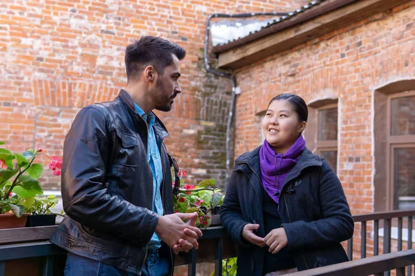 young man and woman talking while standing on the balcony of the