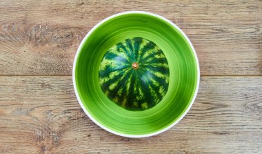 renk natürmort - ahşap bir masanın üstünde yeşil bir tabakta küçük bir karpuz