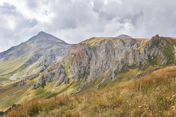 Atmosferik sislerin içinde kayalık bir tepe ile güzel bir dağ manzarası ve ön grubunda sonbahar dağlık bir çayır.