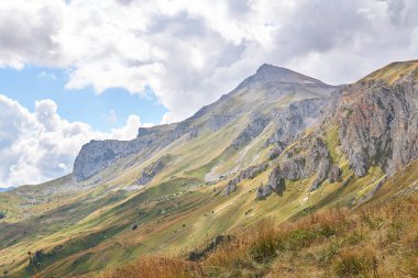 Atmosferik sislerin içinde kayalık bir tepe ve ön planda sonbahar otlağı olan güzel dağ manzarası.