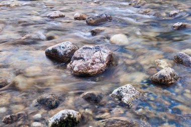 Doğal arkaplan - hızlı bir dağ deresinde taşlar, su hareket halinde bulanıklaşır