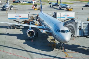 Moskova, Rusya - 16 Eylül 2020: Sheremetyevo havaalanındaki bir jet köprüsünü kullanarak uçağa binen yolcular, arka planda yapım aşamasındaki bir pist