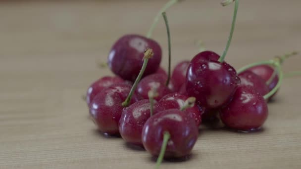 Bayas de cereza jugosas húmedas acostadas en una mesa de madera — Vídeos de Stock