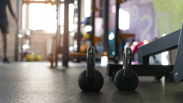 Due kettlebell neri sul pavimento della palestra sportiva — Foto Stock