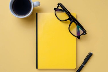 Parlak sarı arka planda kahve, defter, gözlük ve Ofis Kırtasiye