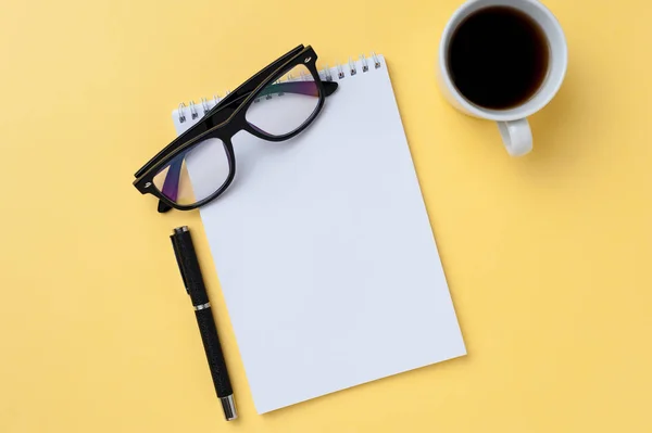 Café, caderno, óculos e artigos de escritório sobre fundo amarelo brilhante — Fotografia de Stock