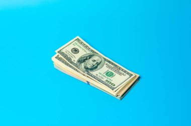 Mavi arka plan üzerinde Amerikan doları banknot yığını.