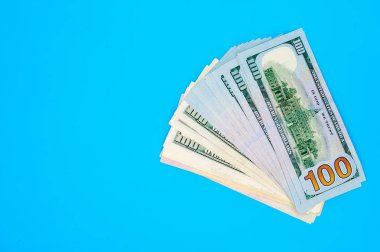 Mavi arka plan üzerinde Amerikan doları banknot yığını.
