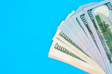 Mavi arka plan üzerinde Amerikan doları banknot yığını.