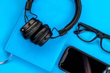 Mavi arka planda siyah şık kulaklıklar.