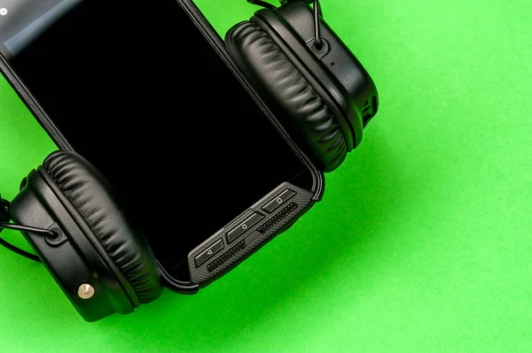 Black stylish headphones on green background.