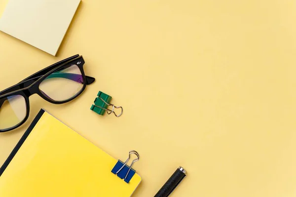Cuaderno, anteojos y papelería de oficina sobre fondo amarillo brillante — Foto de Stock