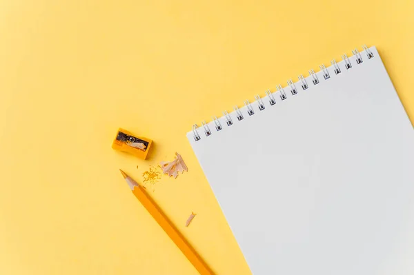 明るい黄色の背景に空のノートブックと鉛筆 — ストック写真