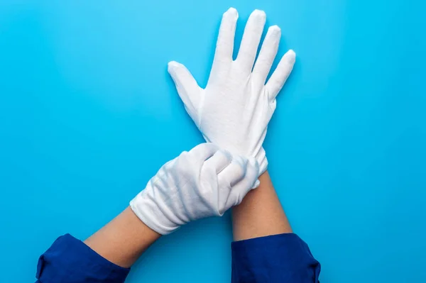 Dvě ženské ruce, které nosí bílé rukavice na modrém pozadí — Stock fotografie