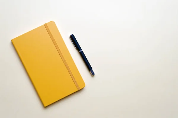 Ноутбук и ручка на желтом фоне — стоковое фото