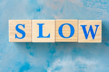 Mavi masada kelime Yavaş ile Ahşap küpler.