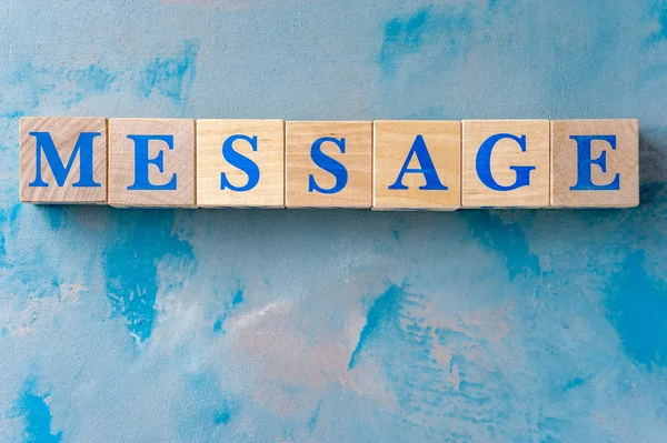 Cubes en bois avec mot MESSAGE sur table bleue . — Photo