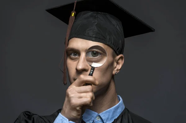 Portrait of young handsome graduate guy with a magnifying glass — Stock Photo, Image
