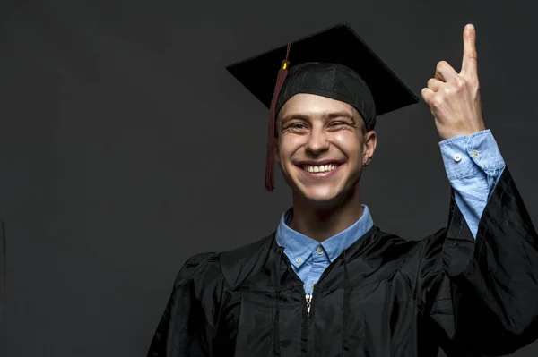 Portrait of graduate adult male student in black graduation gown with hat — Stock Photo, Image