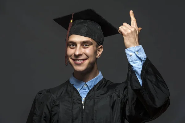 Portrait of graduate adult male student in black graduation gown with hat — Stock Photo, Image