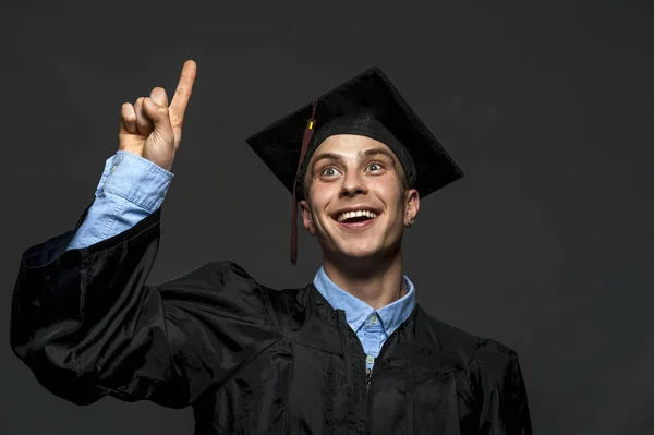 Portrait of graduate adult male student in black graduation gown with hat — Stock Photo, Image