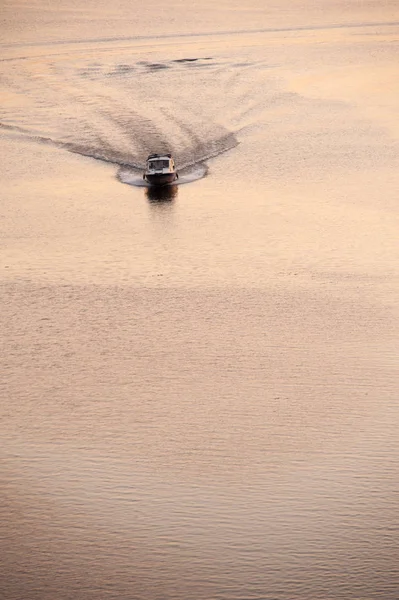 The motor boat floats on a flat sea surface