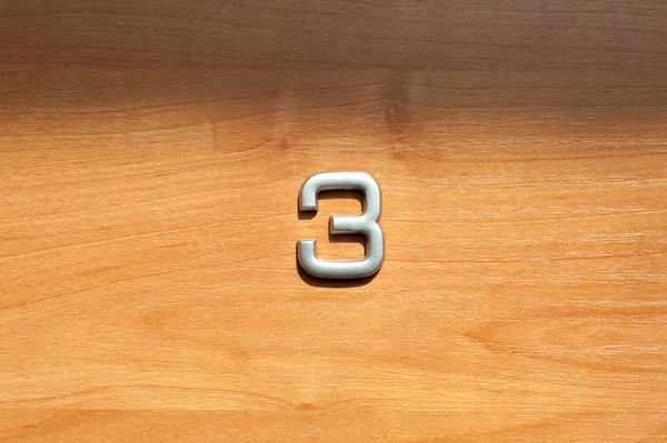 Table number three hanging on a wooden door — Stock Photo, Image