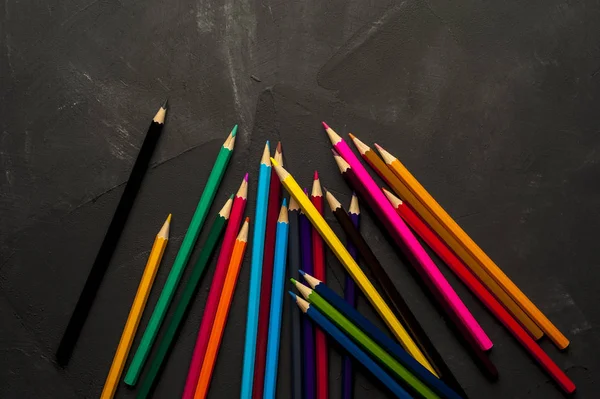 Färgade slipade blyertspennor ligga på den mörka ytan — Stockfoto