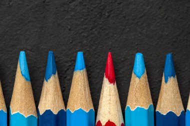 Mavi kalemler arasında kırmızı bir kalemin yakın çekimi yer alır