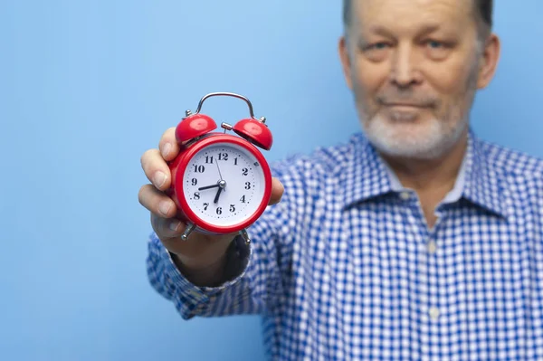 Homem idoso em óculos com um pequeno relógio vermelho — Fotografia de Stock