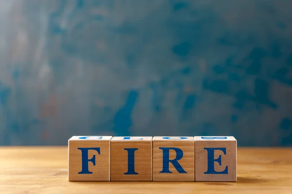 Wooden cubes with word FIRE on blue table.