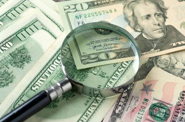 Büyüteç etrafa saçılmış doların üstünde