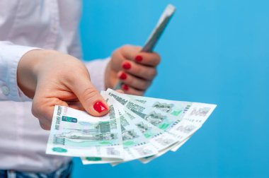 Bir paket Rus rublesi tutan kimliği belirsiz genç bir kadının elleri.