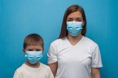 Koruyucu tıbbi maske takan Kafkas anne ve oğlunun portresi..