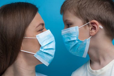 Beyaz anne ve oğul koruyucu bir maske takıp birbirlerine bakıyorlar.