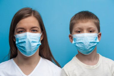 Beyaz anne ve oğul koruyucu tıbbi maske takıyor..