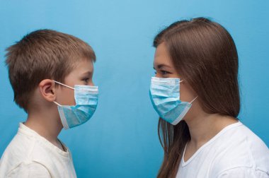 Beyaz anne ve oğul koruyucu tıbbi maske takıyor..