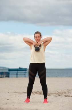 Spor salonunda ağırlık kaldıran kadın ağırlık kaldırıyor..