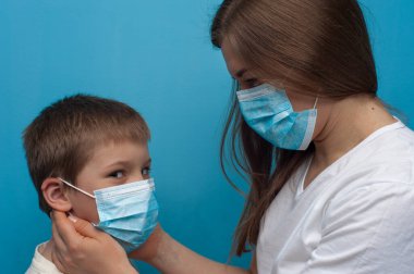 Koruyucu tıbbi maske takan Kafkas anne ve oğlunun portresi..