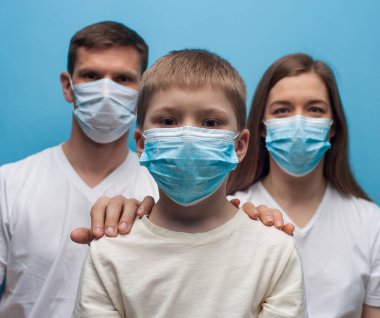 Koruyucu tıbbi maske takan anne ve baba ve çocuk.
