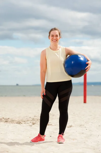 Athletic woman with medicine ball at outdoor fitness gym.