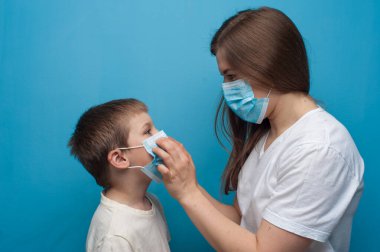 Koruyucu tıbbi maske takan Kafkas anne ve oğlunun portresi..