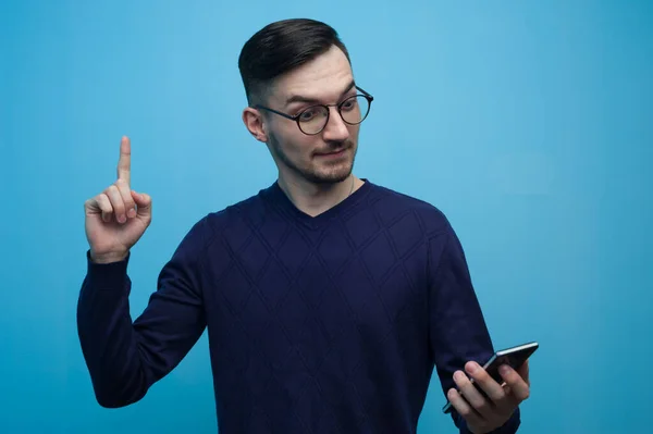 Ritratto di un giovane divertente con gli occhiali che vede qualcosa di utile in uno smartphone — Foto Stock