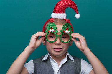 Noel Baba şapkalı küçük bir çocuğun portresi ve Noel ağaçlı komik gözlükler.