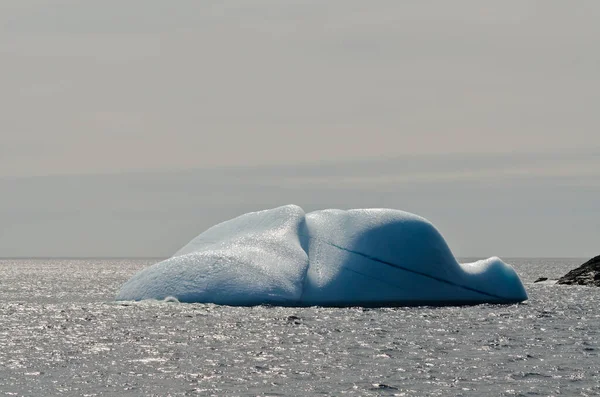 Leuchtend Weißer Eisberg Auf Dunklem Wasser Und Felshintergrund — Stockfoto