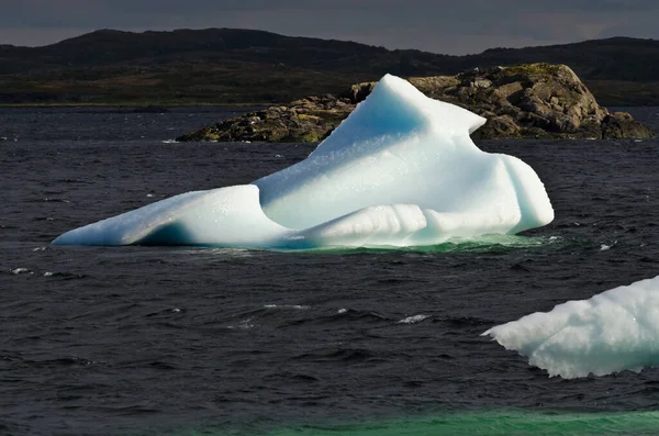 深色水和岩石背景上明亮的白色冰山 — 图库照片