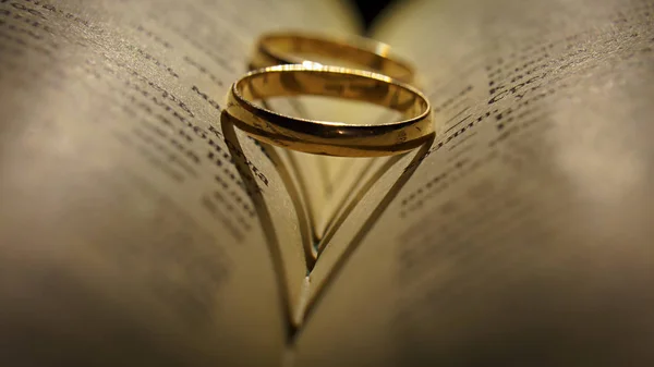 Gold wedding rings on an extended book