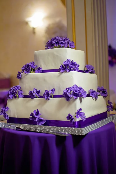 Three-tiered white cake with purple flowers